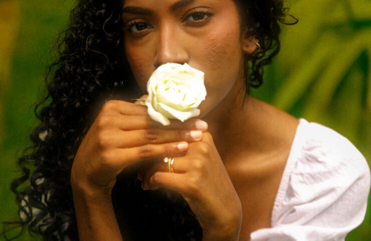 Sri Lankan woman with long natural curls holding a white rose to her face