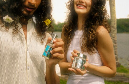 Man and woman with curly hair in white clothing holding Müllwood curl gel and hair mist outdoors in Sri Lanka